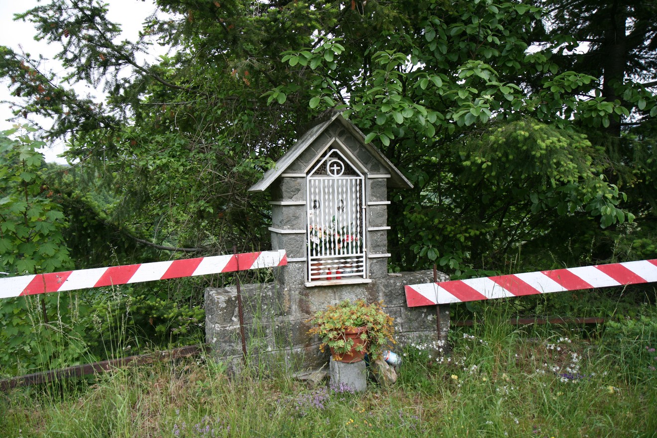 Tabernacolo di Casa Giannino, ornato e circondato da vegetazione, con elementi decorativi e barriere di sicurezza.