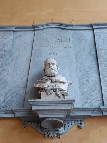 Lapide commemorativa con busto di Garibaldi, dedicata ai caduti per la libertà. Atmosfera storica e di omaggio.