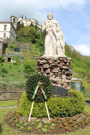 Monumento alla Resistenza con statue di figure storiche, circondato da fiori e vegetazione.