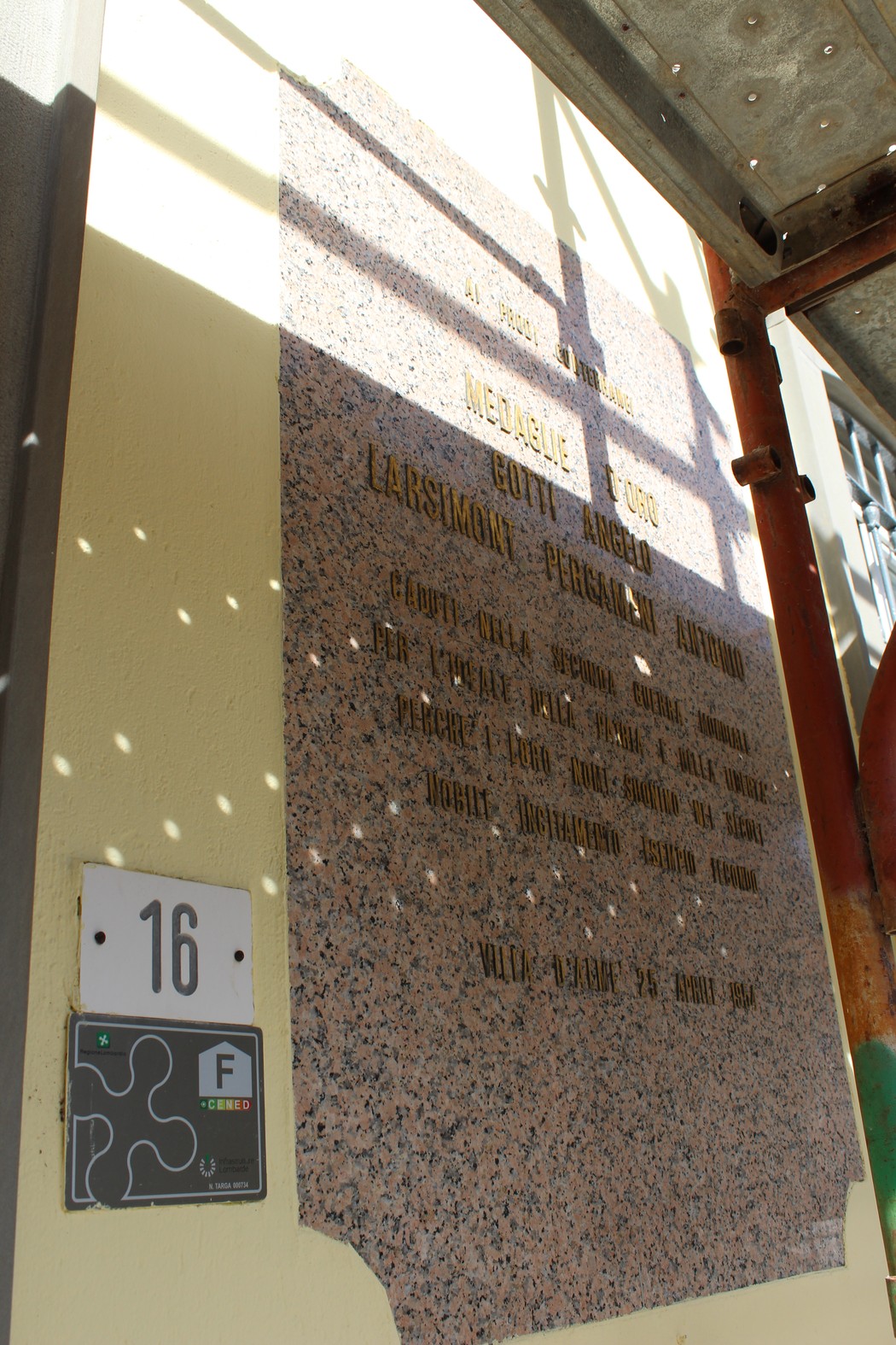 Lapide commemorativa dedicata a Gotti e Larsimont Pergameni, su sfondo murario.