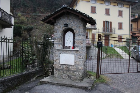 Tabernacolo in pietra con statua al suo interno, situato in un'area residenziale appartata.