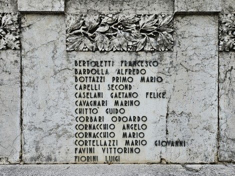 Monumento ai Caduti, con incisi nomi di soldati in memoria dei sacrifici. Ambiente sobrio e rispettoso.