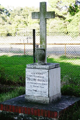 Cippo commemorativo dedicato a Aristide Bragazzi, situato in un'area verde con recinzione.