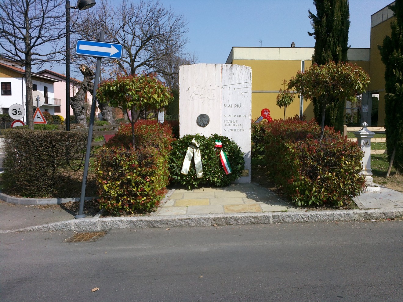 Monumento dedicato alle vittime dell'eccidio di Villa Rossi, circondato da vegetazione e simboli commemorativi.