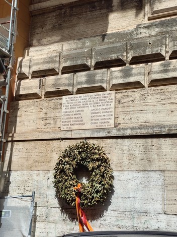Lapide commemorativa dedicata ai rastrellati di via Rasella, ornata con un grande lauro.