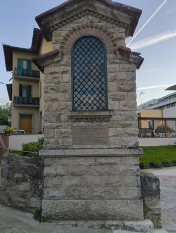 Tabernacolo storico in pietra, con grata su un lato e decorazioni artistiche, situato in un contesto urbano.