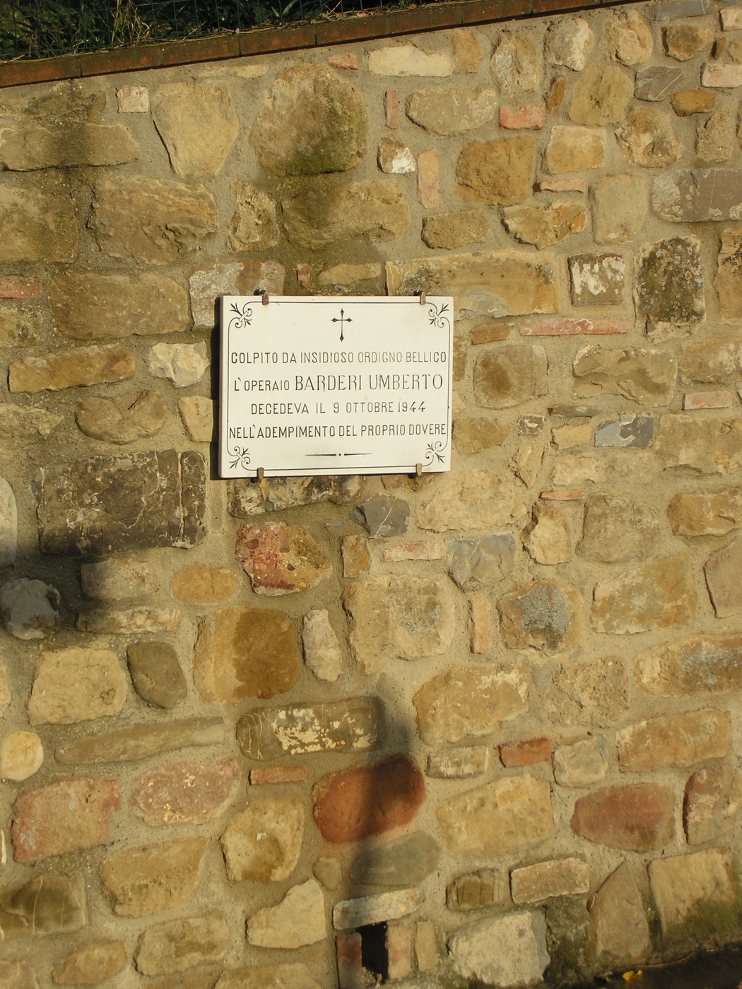 Lapide commemorativa dedicata a Umberto Barderi, collocata su un muro di pietra.