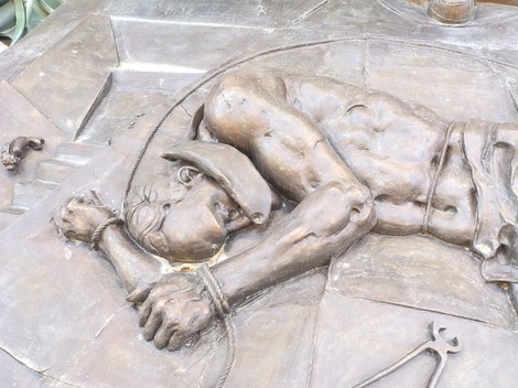 Scultura bronzea che rappresenta una figura umana legata, simbolo di oppressione e memoria storica.