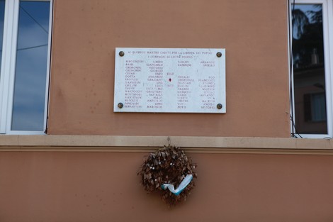 Lapide commemorativa con nomi di caduti per la Libertà, adornata da un'alloro.
