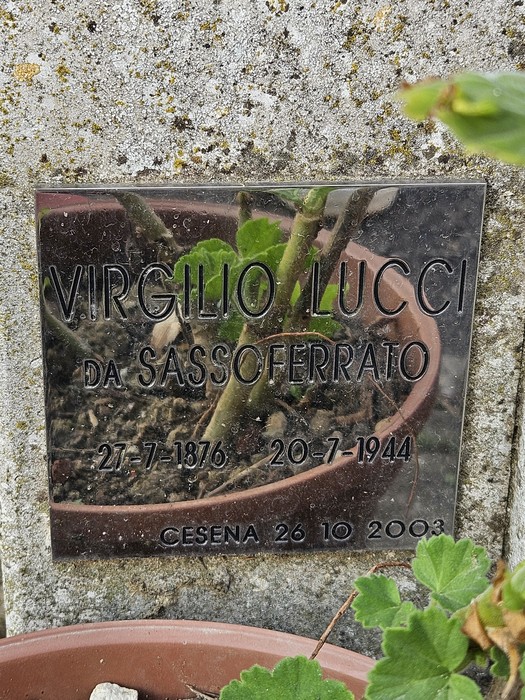 Cippo commemorativo con nome, data di nascita e morte, situato in un'area verde.
