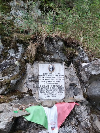 Lapide commemorativa dedicata a Eufemia Gasperoni, situata tra le rocce circondate dalla natura.