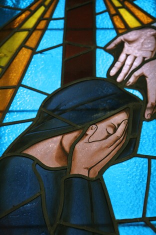 Vetrata della Cappella dei Martiri, che rappresenta una figura in preghiera immersa in luci colorate.