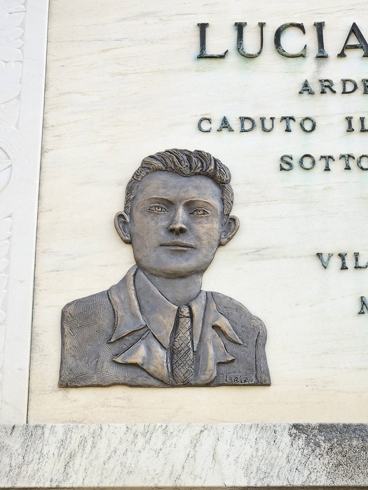 Lapide commemorativa con rilievo di un giovane uomo, in memoria di un caduto. Dettagli in bronzo su marmo.