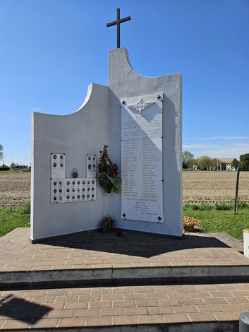 Monumento commemorativo ai Caduti di Valliera, con elenco di nomi e decorazioni floreali in un contesto rurale.