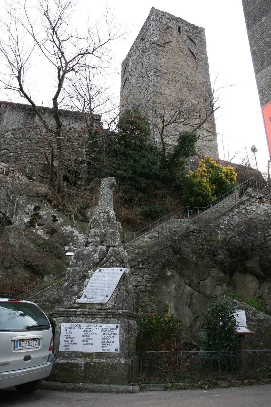 Cippo commemorativo dei caduti di Serravalle, con vista sulla torre e attorno verdeggiante.