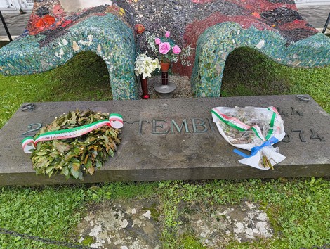 Monumento commemorativo ai martiri della Creda, con corone di fiori e omaggio ai caduti.
