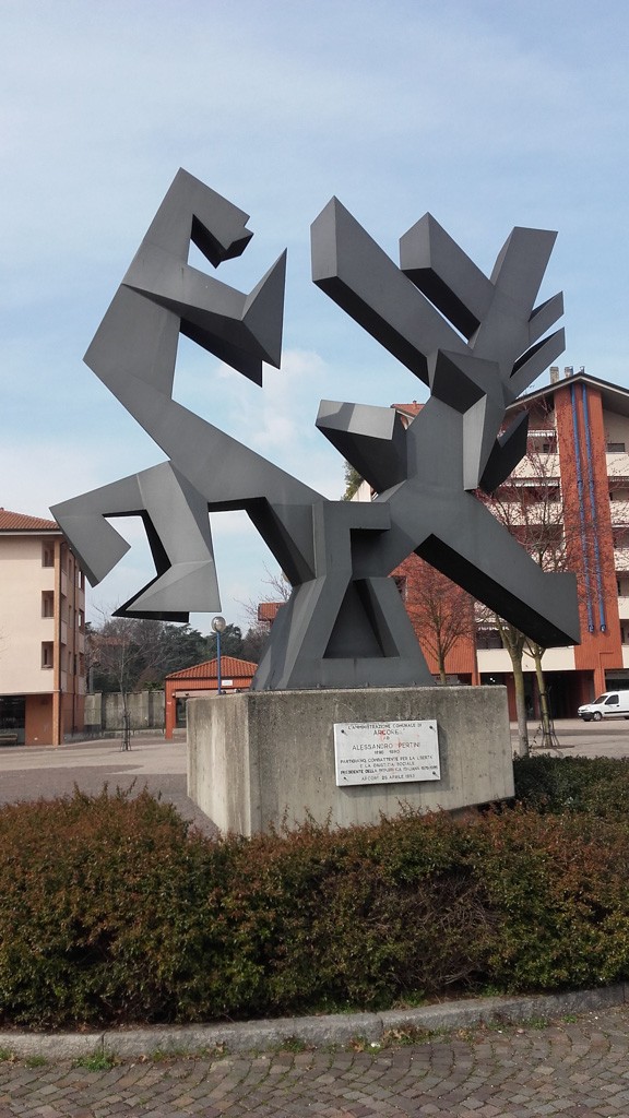 Scultura moderna dedicata a Sandro Pertini, caratterizzata da forme geometriche e linee astratte.