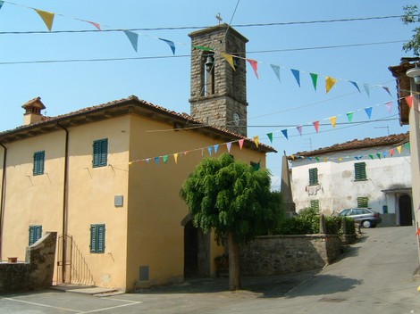 Vista della Lapide di Pulicciano con il campanile e bandierine decorative. Atmosfera di festa nel paese.
