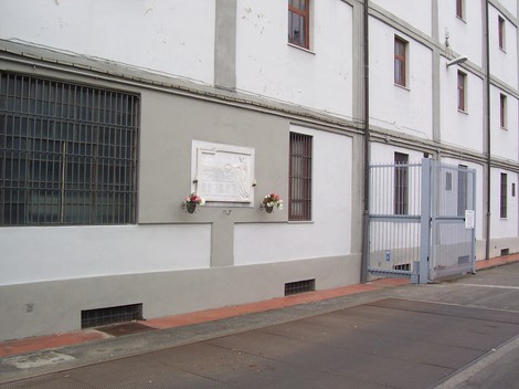 Lapide commemorativa dell'Istituto Farmaceutico Militare su un edificio. Elementi decorativi ai lati.