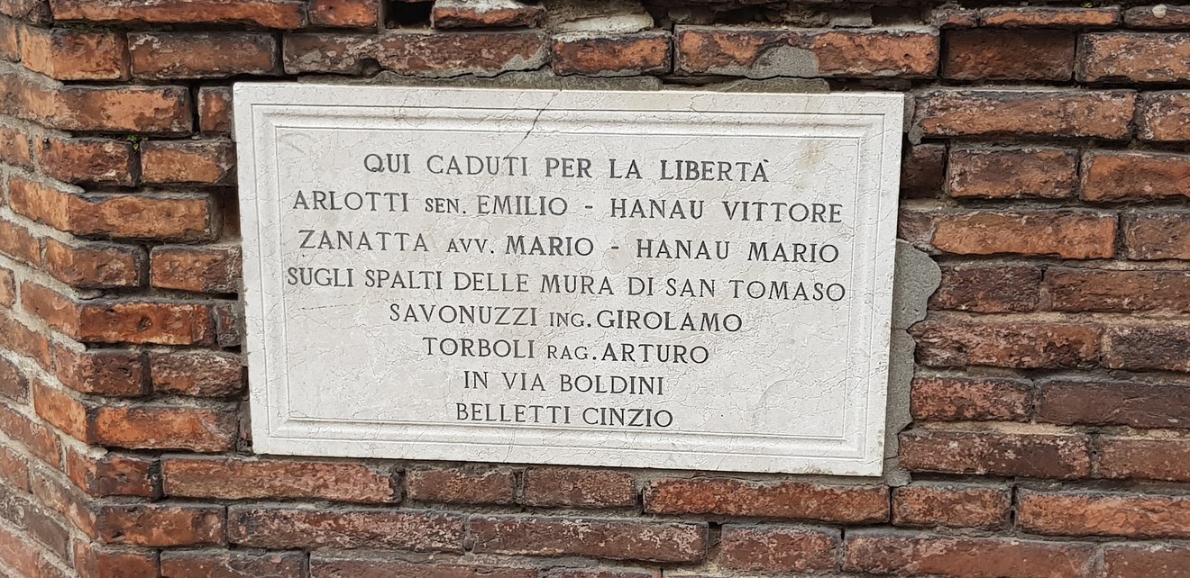 Lapide commemorativa in memoria dei caduti per la libertà, situata su una parete storica.