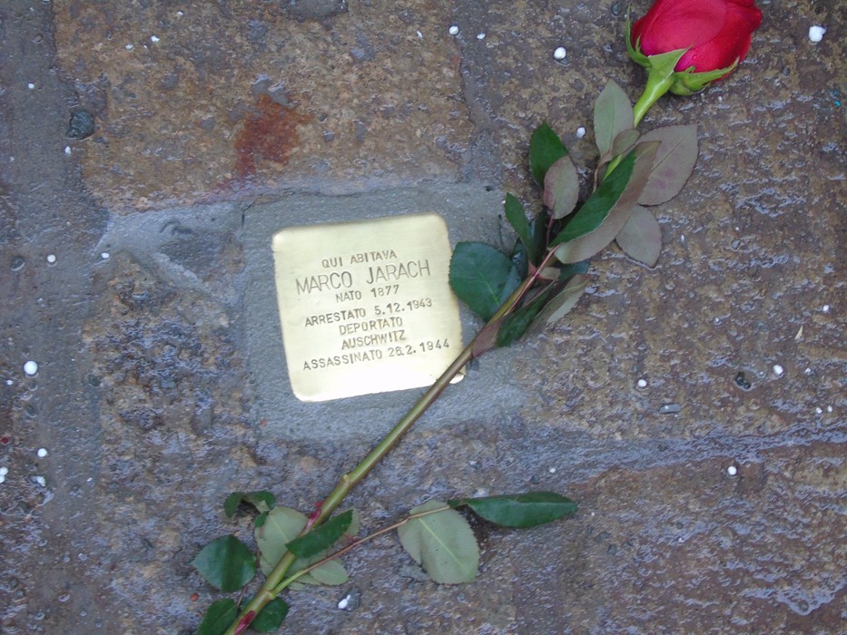 Pietra d'inciampo dedicata a Marco Jarach, con una rosa rossa posata accanto, in memoria della sua storia.