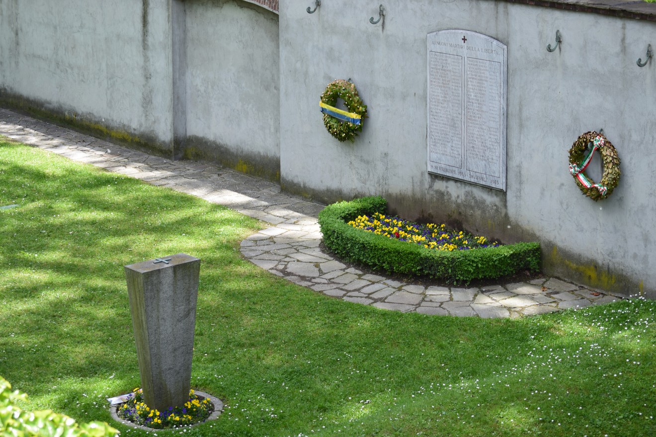 Vista del "Sacrario del Martinetto" con monumenti e fiori in un giardino curato e ben illuminato.
