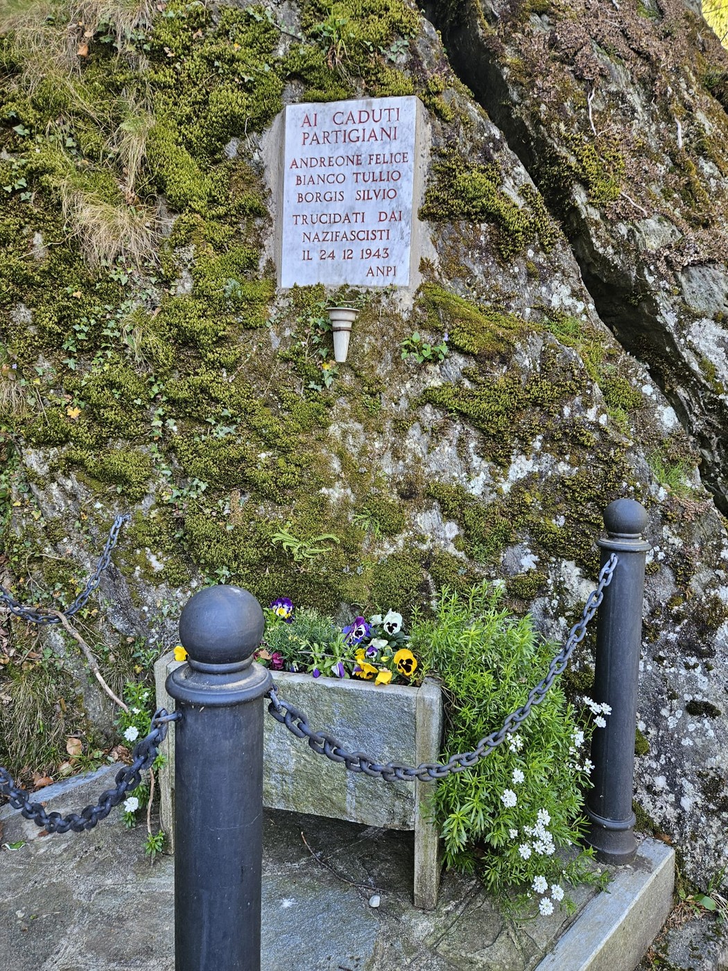 Lapide commemorativa dedicata ai partigiani Andreone, Bianco e Borgis, situata su una roccia.