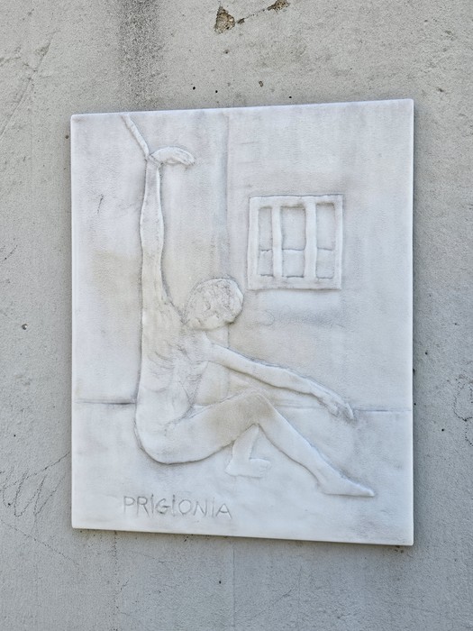 Monumento alla Resistenza, scultura in rilievo di figura umana in pose evocative, su fondo neutro.