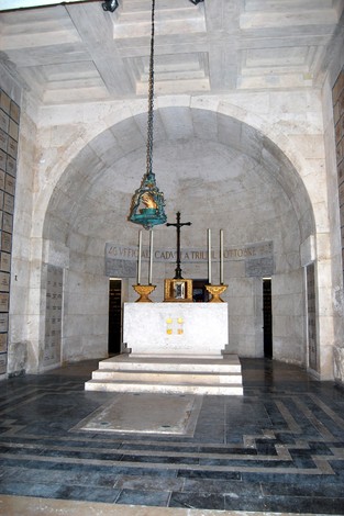 Interno del "Sacrario dei caduti militari a Trilj" con altarino, croce e decorazioni, ambiente sobrio e commemorativo.