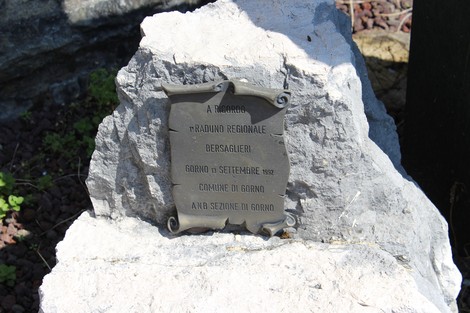 Monumento a Riccardi con targa commemorativa su una pietra, immerso in un contesto naturale.