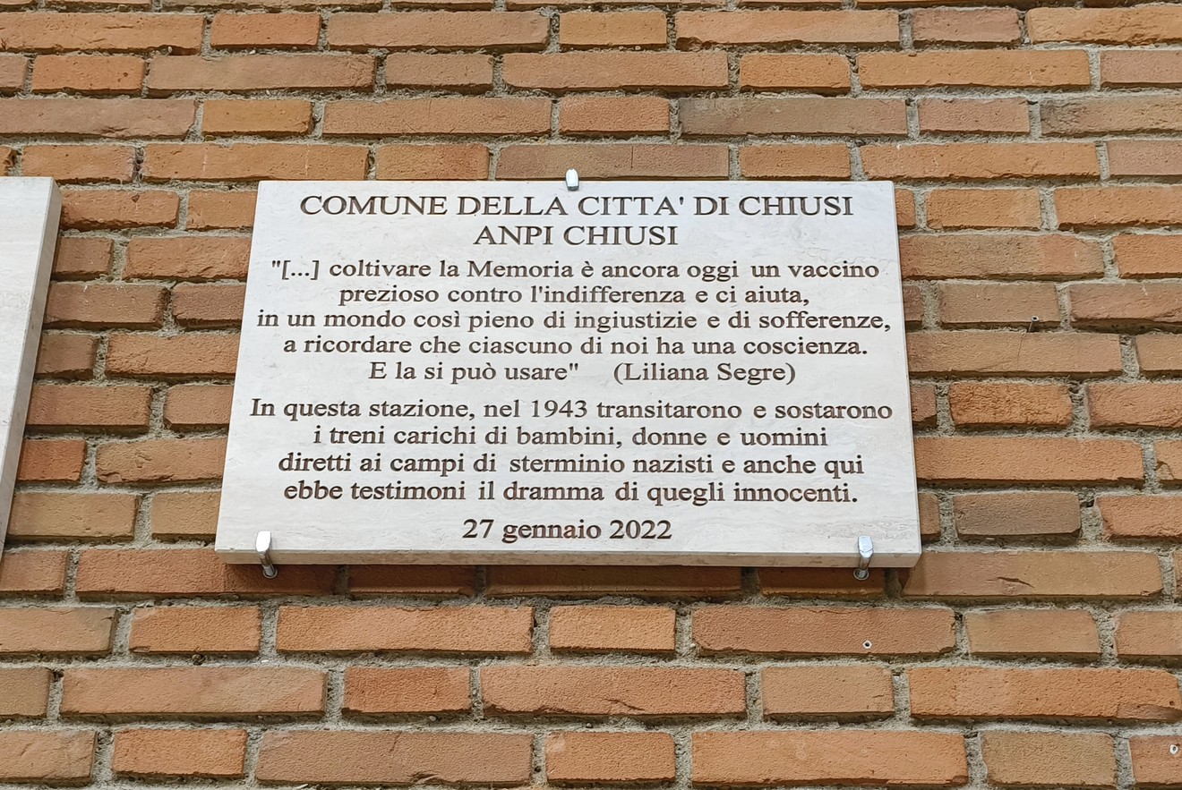 Lapide commemorativa dedicata ai deportati, con riferimenti alla memoria e alla sofferenza umana.