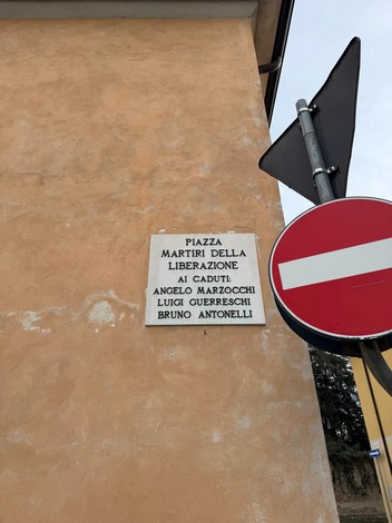Lapide commemorativa ai Martiri della Liberazione, con nomi di caduti su fondo chiaro.
