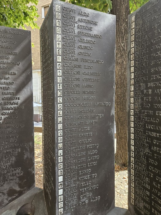 Stele di pietra incise con i nomi dei caduti del Sacrario della Resistenza Reggiana, disposte all’aperto tra gli alberi.
