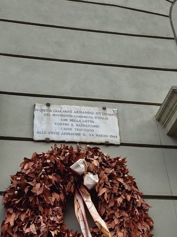 Lapide commemorativa dedicata ad Armando Ottaviano, situata su una parete con una corona di foglie secche.