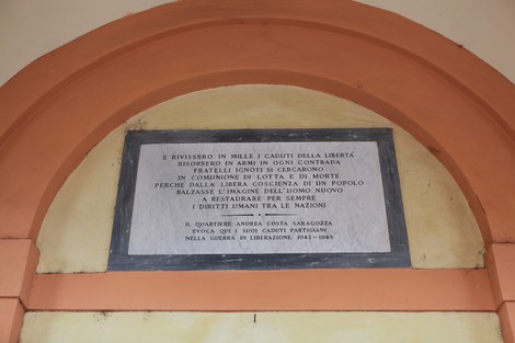 Lapide commemorativa dedicata ai caduti partigiani, collocata in un edificio storico.