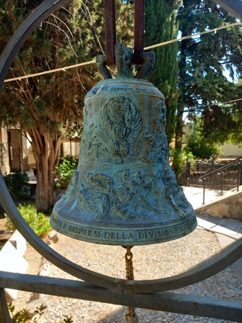 Campana del "Sacrario dei caduti di Kos", con dettagli decorativi e un contesto naturale suggestivo.