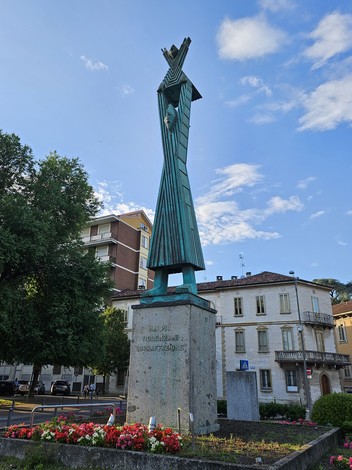 Monumento alla Resistenza, scultura alta con figure stilizzate e decorazione floreale circostante.