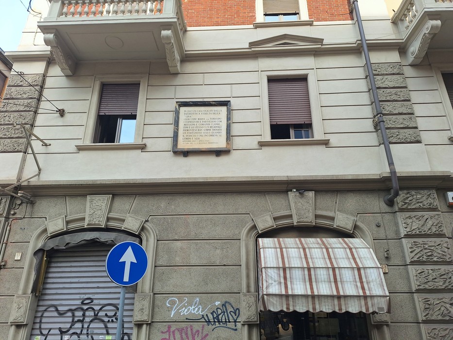 Lapide con iscrizione tra due finestre sulla facciata di un palazzo.