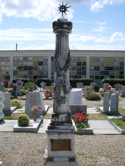 Monumento ai Caduti di Scandiano, commemorazione dei soldati, situato in un cimitero tra fiori e lapidi.