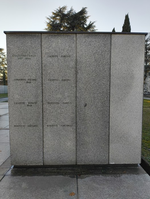 Monumento commemorativo al Campo della Gloria, con nomi di caduti incisi su una parete di pietra.