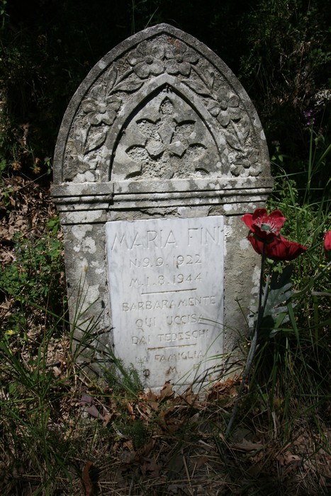 Cippo in memoria di Maria Fini, deceduta nel 1944, circondato da vegetazione.