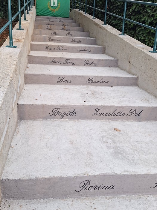 Scalinata in pietra con nomi di donne incisi su ogni gradino, corrimano in metallo ai lati.