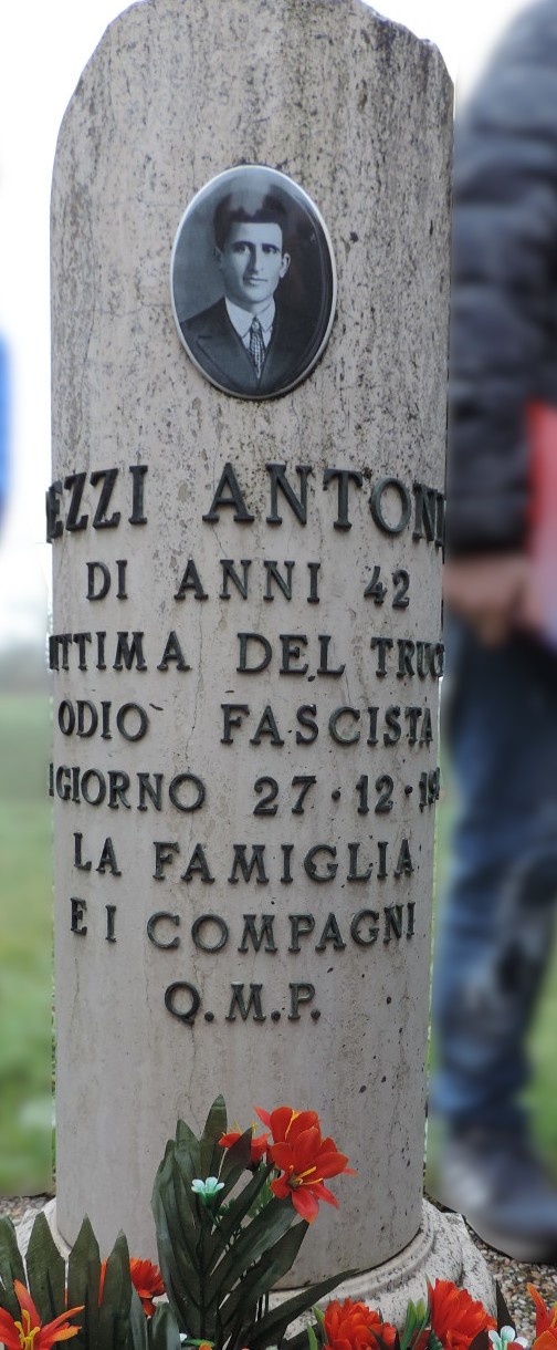 Cippo commemorativo in memoria di Antonio Pezzi, vittima del fascismo, con fiori e foto in omaggio.