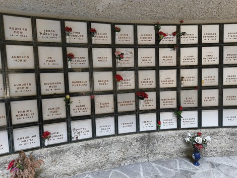 Monumento Ossario dei caduti partigiani, con lapidi in marmo e fiori commemorativi.