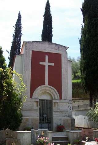 Cappella dei Caduti di Istia d'Ombrone, decorata con una croce e circondata da alberi e piante.
