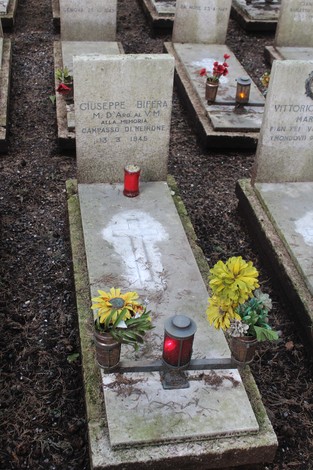 Tombe perpetue dei caduti per la Libertà, decorate con fiori e candele in un cimitero commemorativo.