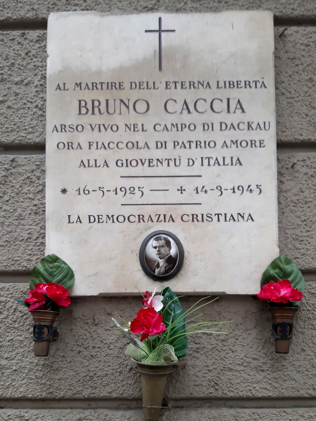 Lapide commemorativa dedicata a Bruno Caccia, martire della libertà, con fiori decorativi.