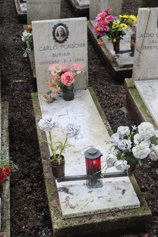Tombe con fiori e lumini, dedicate a caduti per la libertà, in un cimitero commemorativo.