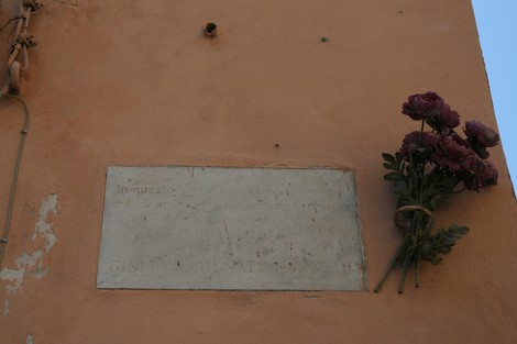Lapide commemorativa per Giselda e Renato Lazzeri, incastonata in una parete, adornata con fiori.