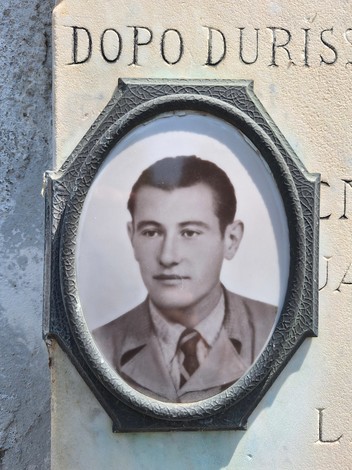 Lapide commemorativa con fotografia di un giovane uomo, in contesto di memoria e ricordo.